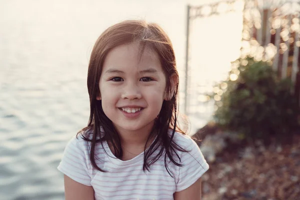 Menina asiática feliz rindo com sol flare fundo por th — Fotografia de Stock