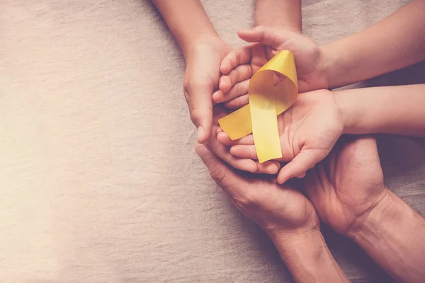 Sarı altın kurdele tutan yetişkin ve çocuk elleri, Sarcoma Awa — Stok fotoğraf