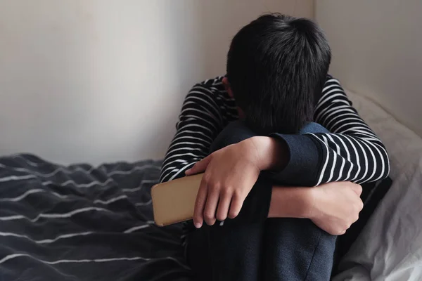 Young Asian preteen teenager boy hugging his knee in his bedroom — Stock Photo, Image