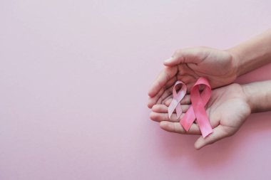 eller pembe arka plan üzerinde pembe kurdeleler tutarak, Meme kanseri awa