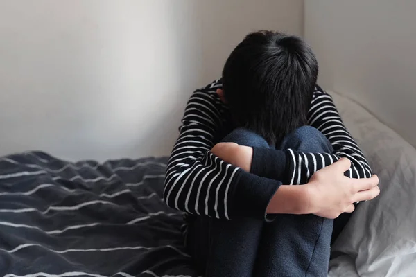 Depressed young preteen teenage boy hugging his knee in bedroom, — Stock Photo, Image
