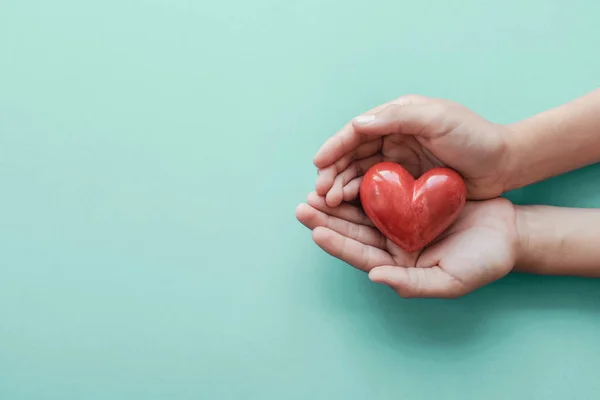 Händer som håller rött hjärta på blå bakgrund, hälsovård, kärlek, o — Stockfoto