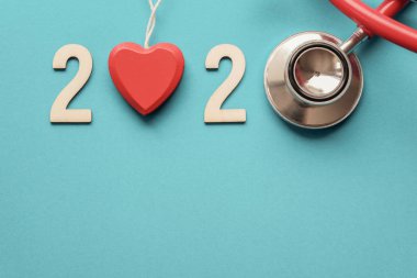Kırmızı stetoskoplu 2020 ahşap sayı. Kalp sağlığı ve sağlık konsepti için Happy New Year, hayat sigortası iş, Yeni Yıl kararları hedef