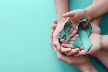 Yetişkin ve çocuk elleri mavi arka plan üzerinde Teal şeritler tutarak