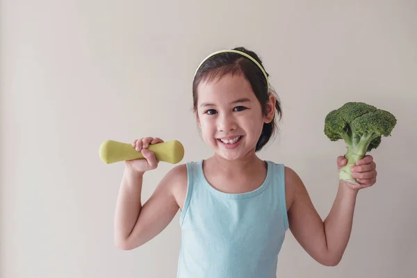 Feliz y saludable mixta asiática chica levantando un brócoli y un mudo — Foto de Stock