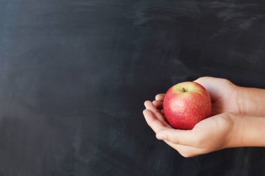 Öğrenci elleri karatahta geçmişi olan kırmızı elmayı tutuyor, Happ