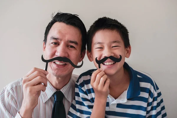 Feliz pai misto e filho pré-adolescente se divertindo com bigode falso — Fotografia de Stock