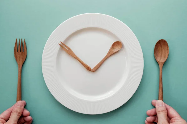 Cucchiaio di legno e forchetta come lancette dell'orologio su piatto bianco, Intermitt — Foto Stock