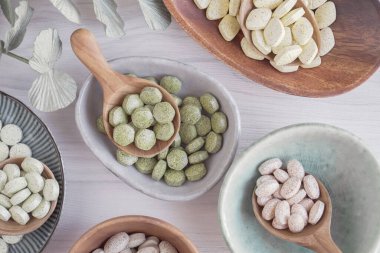 Doğal çarmıhlı sebzeler ve tahta kaşıklarda alternatif bitkisel haplar, sağlıklı bağırsak diyetleri için keto diyet takviyeleri.