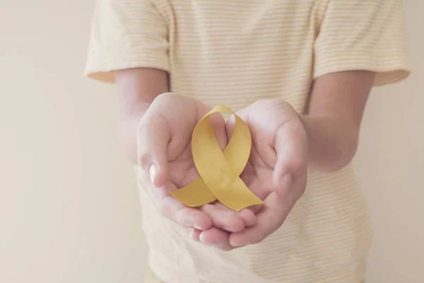 Mãos Segurando Fita Ouro Amarelo Consciência Sarcoma Câncer Ósseo Consciência — Fotografia de Stock