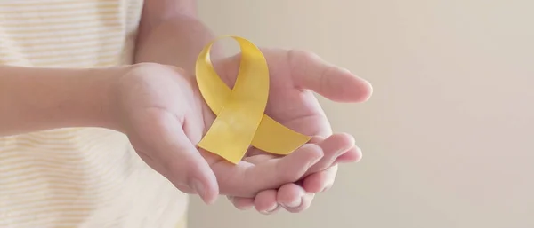 Mãos Segurando Fita Ouro Amarelo Consciência Sarcoma Câncer Ósseo Consciência — Fotografia de Stock