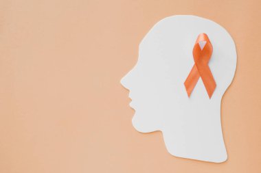 Turuncu arka planda kağıt kafa beyni üzerine turuncu kurdele dikkat eksikliği hiperaktivite bozukluğu ADHD farkındalığı, zihinsel sağlık konsepti