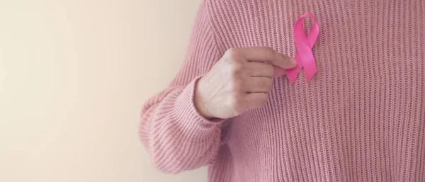 woman hand holding pink ribbon, breast cancer awareness, October pink, World cancer day concept