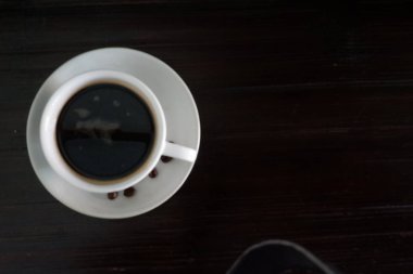 Kahve fincanı ve kahve çekirdekleri ahşap masada, mesaj için yer var.