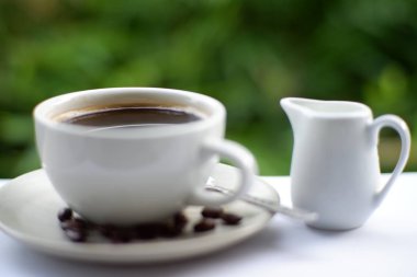 Eski ahşap masa arkasında kahve fincanı ve kahve çekirdekleri. Mesaj için yer var.