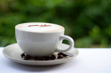 Eski ahşap masa arkasında kahve fincanı ve kahve çekirdekleri. Mesaj için yer var.