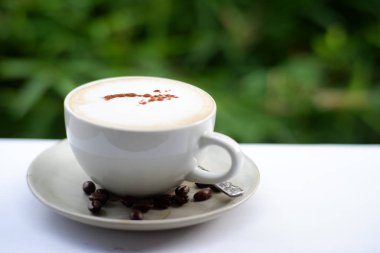 Eski ahşap masa arkasında kahve fincanı ve kahve çekirdekleri. Mesaj için yer var.