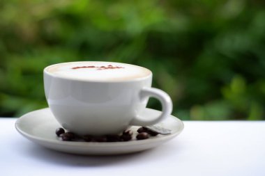 Eski ahşap masa arkasında kahve fincanı ve kahve çekirdekleri. Mesaj için yer var.