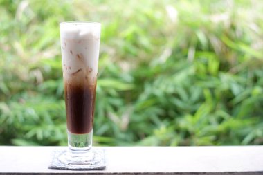 Eski ahşap masa arkasında buzlu kahve ve kahve çekirdekleri, mesaj için yer.