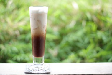 Eski ahşap masa arkasında buzlu kahve ve kahve çekirdekleri, mesaj için yer.