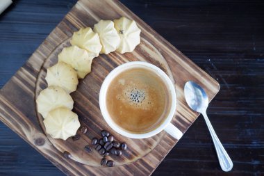 Eski ahşap masa arkasında kahve fincanı ve kahve çekirdekleri. Mesaj için yer var.