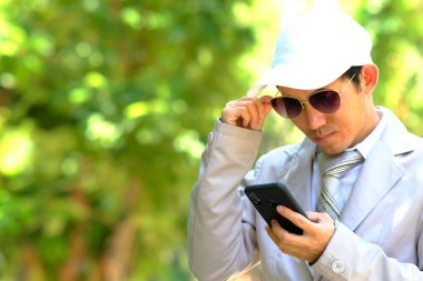 İş adamı akıllı telefon kullanıyor ve açık havada iş yapıyor.