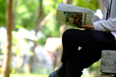 İş adamı akıllı telefon kullanıyor ve iş gazetesi okuyor.
