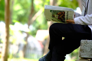 İş adamı akıllı telefon kullanıyor ve iş gazetesi okuyor.