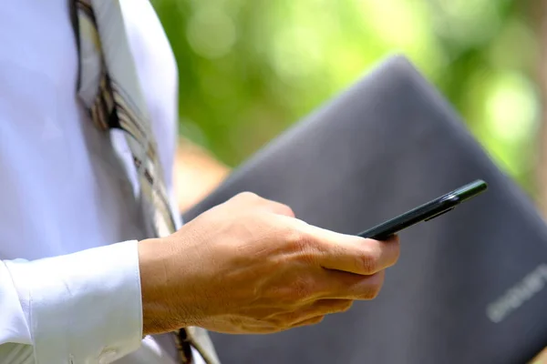 公園でスマートフォンを使ってオンラインで仕事をしているビジネスマンが — ストック写真
