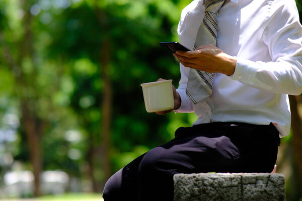 businessman using smartphone and reading a business news out door