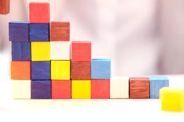 Businessman hand holding wooden cube block on table background and business concept growth success process and plan growth and increase of positive indicators in his business