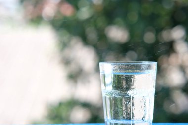 Ahşap arka planda bir bardak su ve içme suyu.