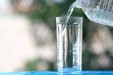 Ahşap arka planda bir bardak su ve içme suyu.