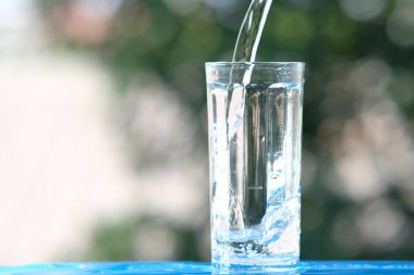 Ahşap arka planda bir bardak su ve içme suyu.