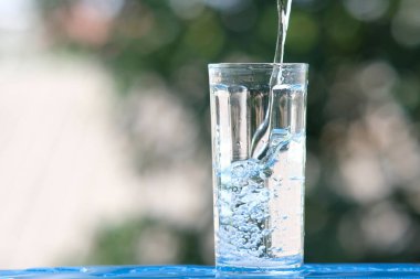 Ahşap arka planda bir bardak su ve içme suyu.