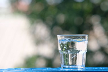 Ahşap arka planda bir bardak su ve içme suyu.