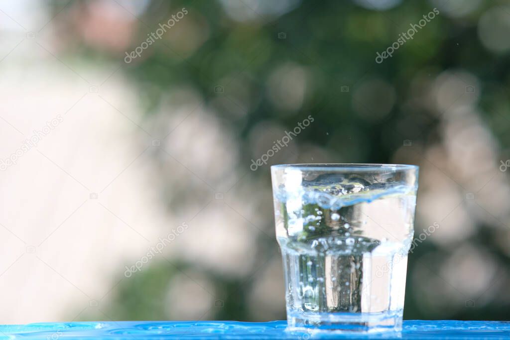Glass of water on wood table background and pouring drinking water
