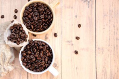 Kahve fincanı ve kahve çekirdekleri ahşap masada, mesaj için yer var.