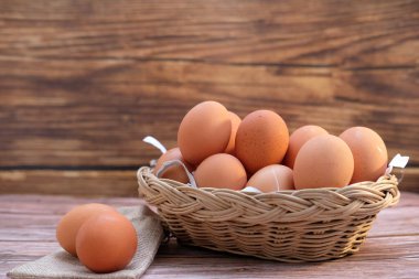 Tahta arka planda sepetteki tavuk yumurtaları ve metin için boşluk