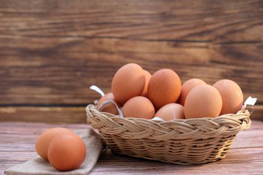 Tahta arka planda sepetteki tavuk yumurtaları ve metin için boşluk