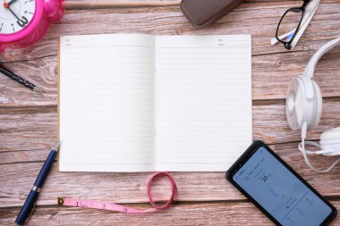 Telefon, okuma gözlüğü ve kalemle defteri aç 