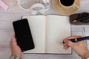 Üst düzey bir iş adamı elinde akıllı bir telefonla masada çalışıyor.