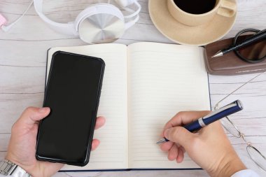 Üst düzey bir iş adamı elinde akıllı bir telefonla masada çalışıyor.