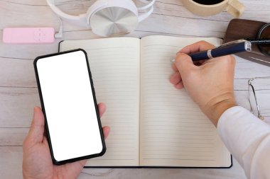 Üst düzey bir iş adamı akıllı telefon kullanıyor ve masada çalışıyor.