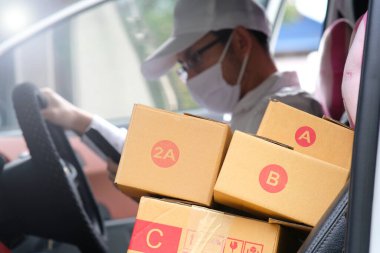 Paketli teslimatçı, arabanın yanında karton kutular.