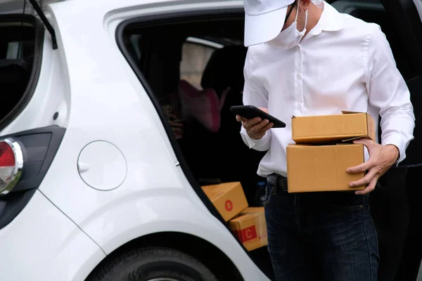 delivery man with parcels, cardboard boxes next to the car