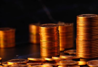 Siyah arka planda altın para yığını ve reklam paraları finans ve bankacılık, artan altın madeni para sütunları masa üzerinde