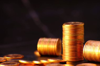 Siyah arka planda altın para yığını ve reklam paraları finans ve bankacılık, artan altın madeni para sütunları masa üzerinde