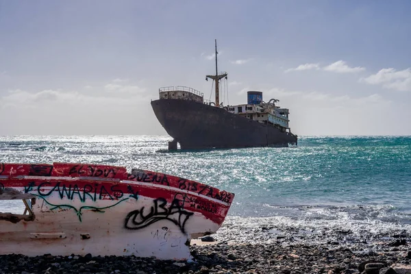 Shipwreck, an old steel cargo ship, off the coast of the Canary Island of Lanzarote. In the foreground are the remains of a wooden fishing boat.