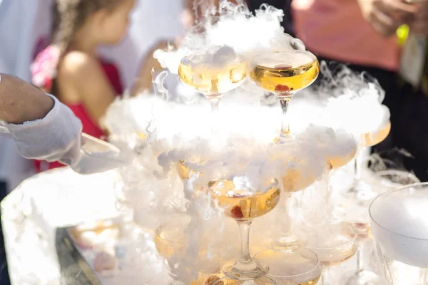 Champagneglas. Pyramid eller fontän av champagneglas med körsbär och ånga från torr is — Stockfoto